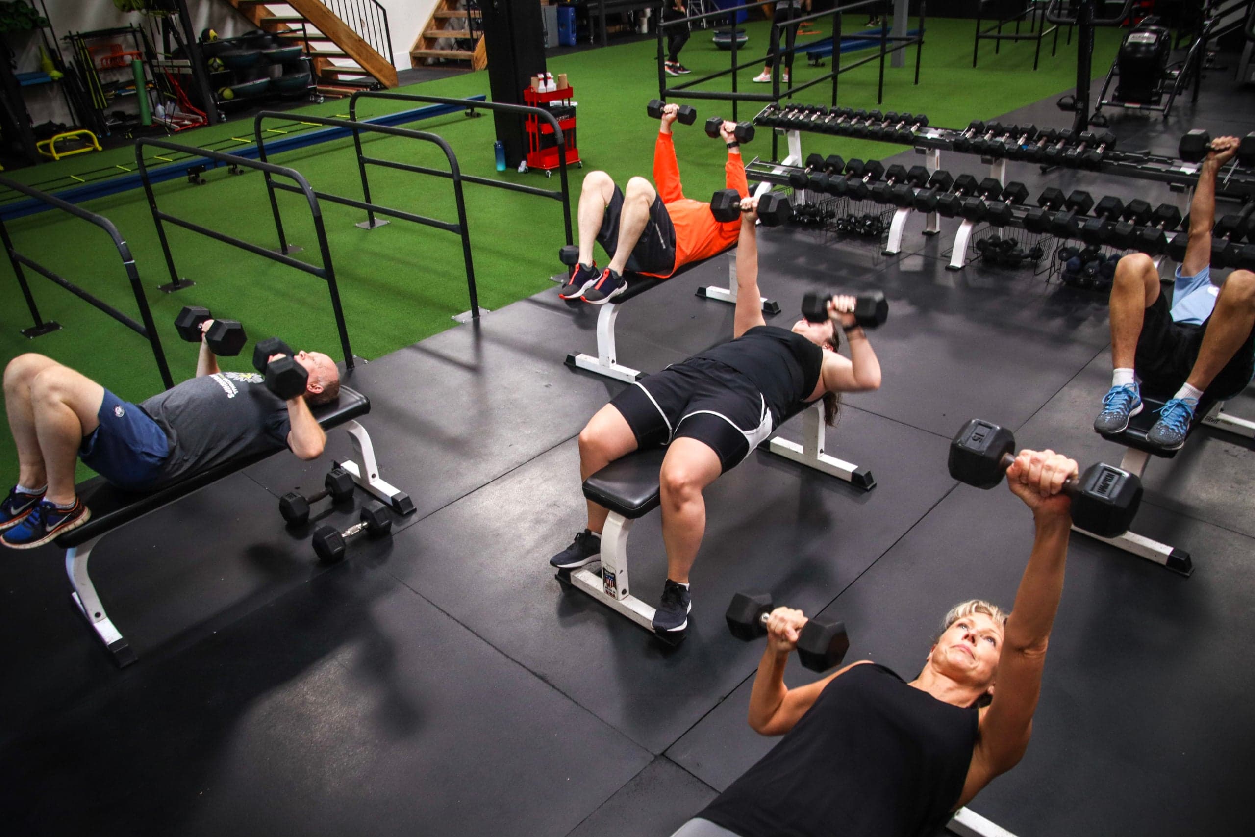 Small-group strength training at ADAPT: members on dumbbell benches