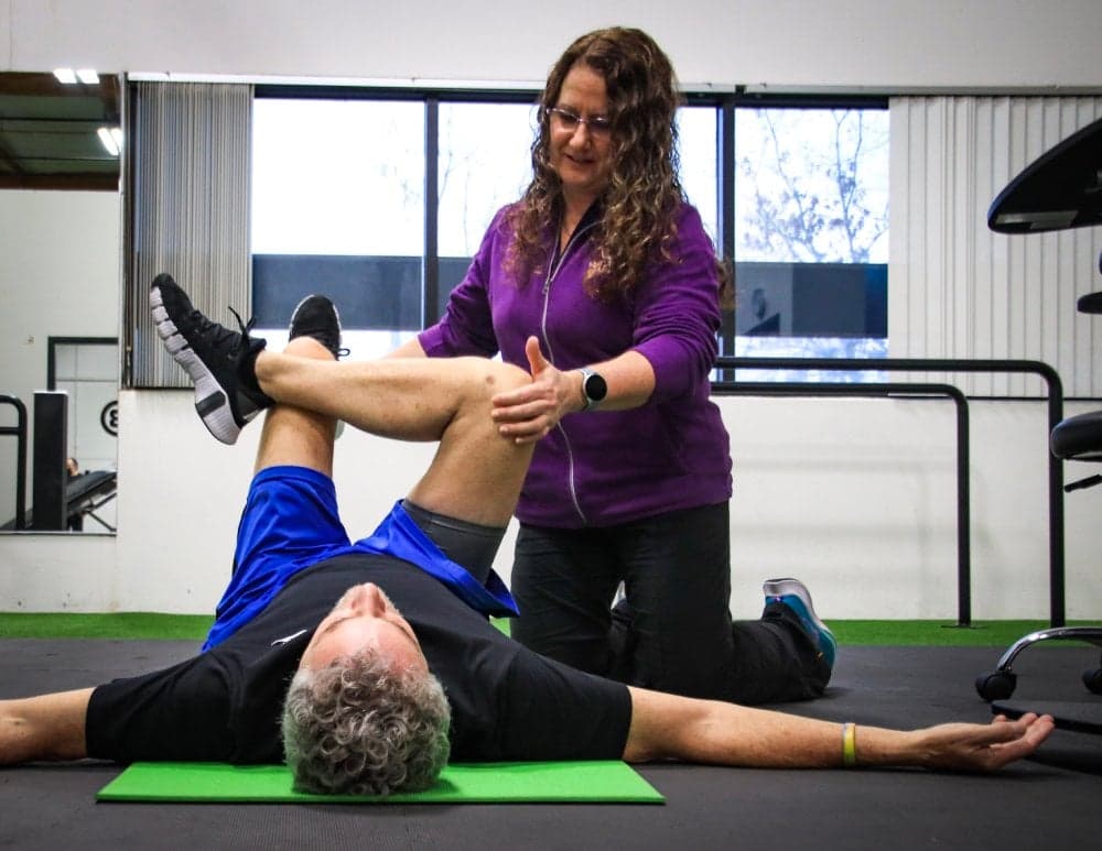 ADAPT physical therapist guiding a client through knee mobility on a treatment table