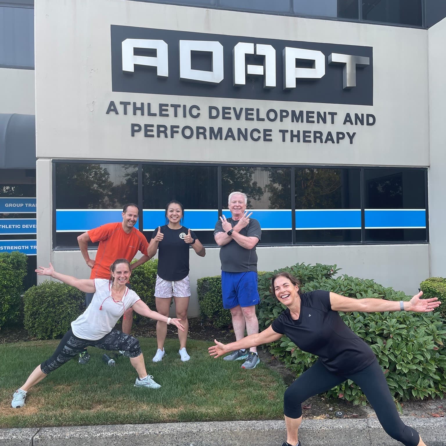 Members posing under the ADAPT building signage in Beaverton