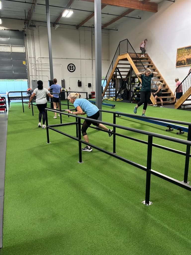 Members training on parallel bars in the ADAPT Advanced area, A-frame stairs in background